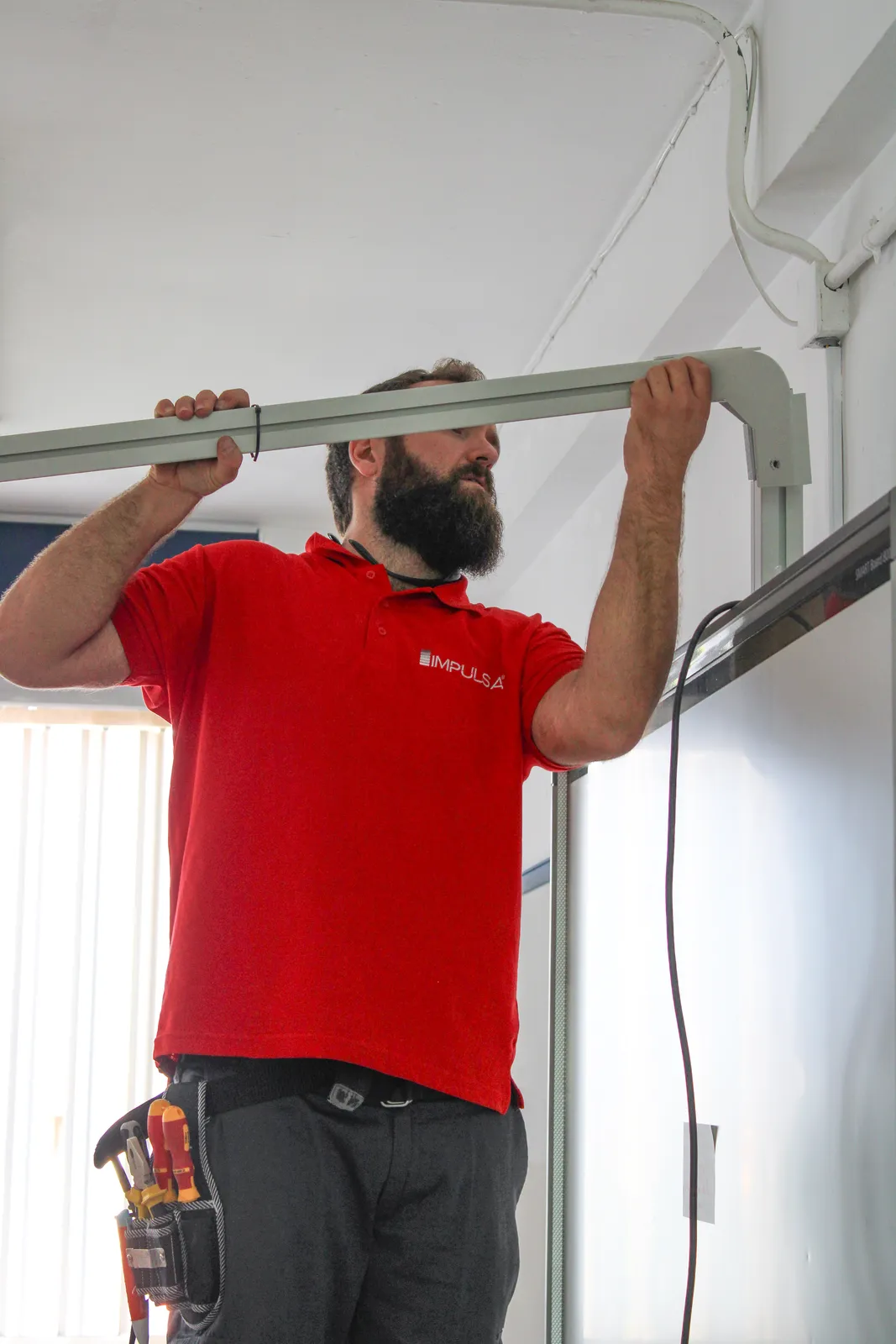 Técnico de Impulsa con polo rojo desinstalando mástil de pantalla antigua